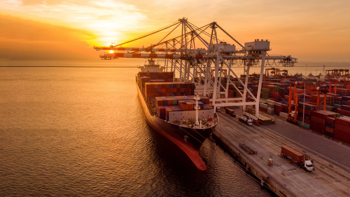 Crane loading cargo container at sunset