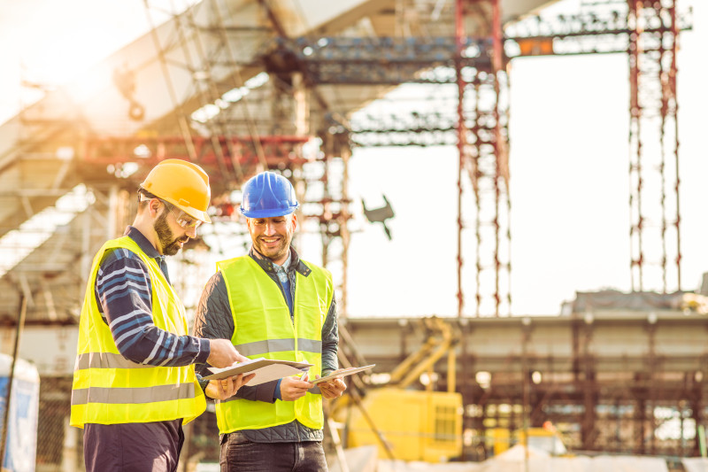 Construction manager reviewing payment practices reporting and liquidity risks on-site with tablet